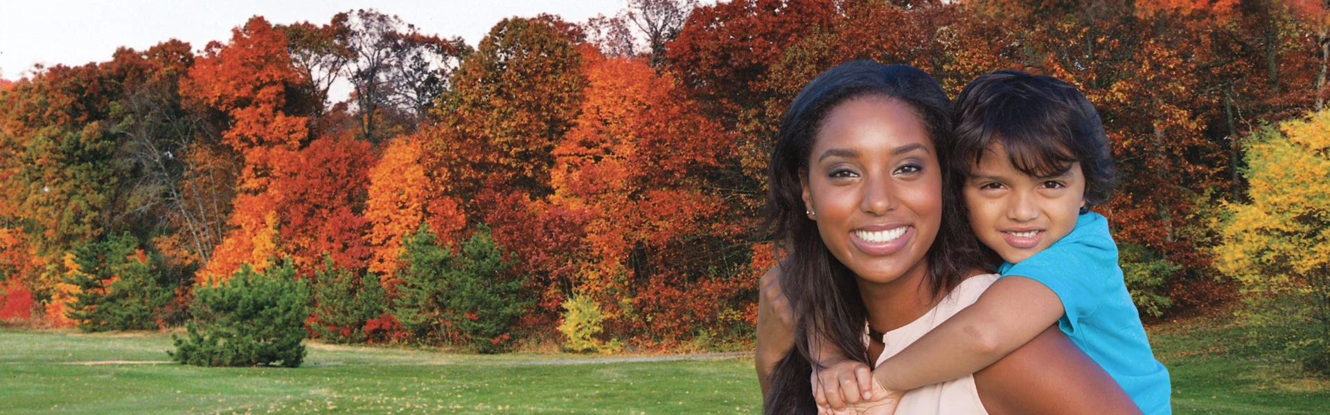 Mother and son in a field of fall trees.